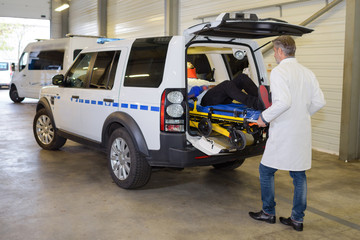 Paramedic loading stretcher into ambulance vehicle