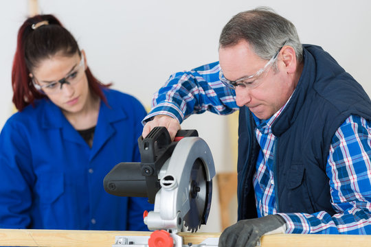 student and teacher in carpentry class using circular saw