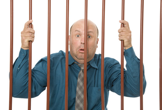  Businessman In Jail Behind Bars With A Sad Expression.