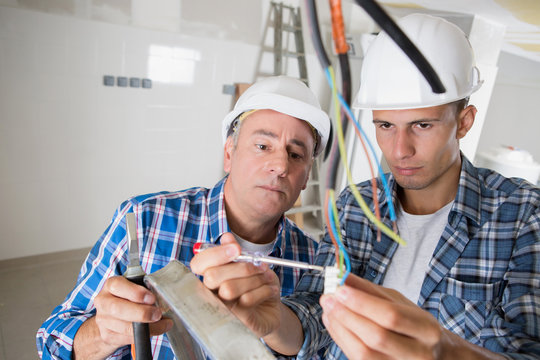 Men using electrical screwdriver to test cables