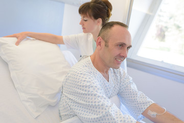 nurse helping patient in bed in hospital