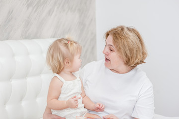 grandmother talking to her granddaughter on the bed