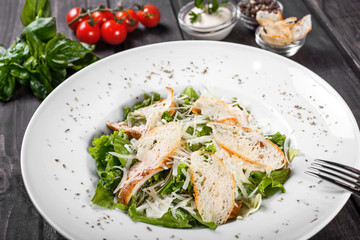 Salad with chicken breast, parmesan cheese, croutons, mixed greens, lettuce on wooden background. Healthy food