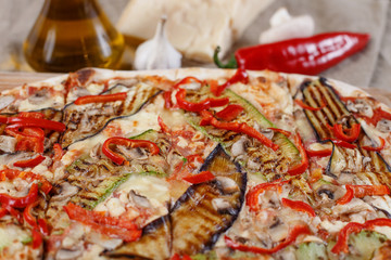 Delicious pizza with chicken, zucchini, eggplant, pepper, cheese and mushrooms on wooden rustic table. Top view. Toning