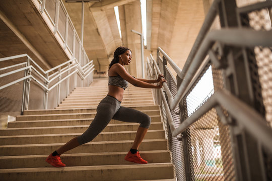 Young Black Athletic Girl Doing Stretching Exercise On Stairs