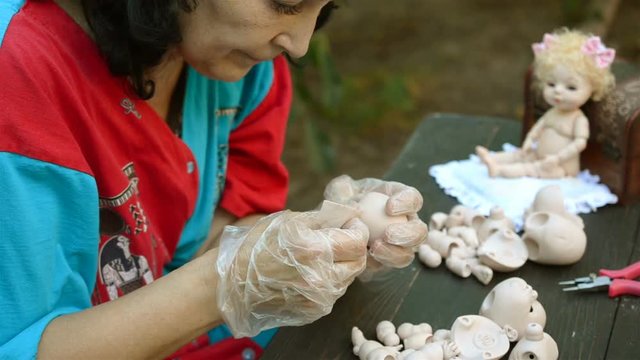 Woman artist make dolls of BJD or reborn in the workplace. Processing the workpiece. The concept of the craft of the master manufacturer of dolls. Selective focus. Close-up.