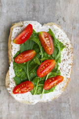 Top view of open sandwich with arugula and cherry tomato