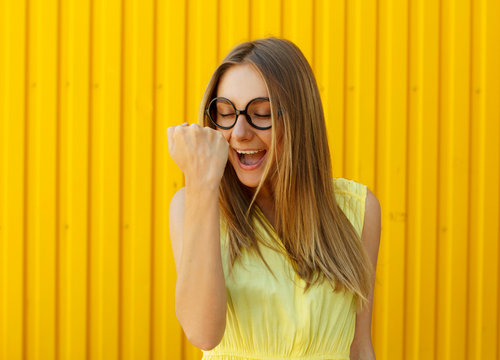 Portrait of a thoughtful girl wearing toy funny glasses celebrating her success over yellow background