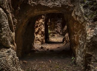 View to small tunnel in big hard rock leading to green forest in Cerro del Hierro, Seviile