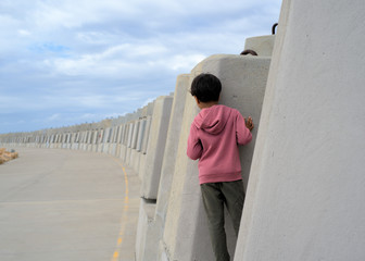 Kid peeking from behind the wall. Outdoor setting. Child hiding behind wall.
