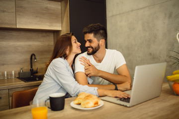 Couple in love enjoying breakfast and using laptop together.