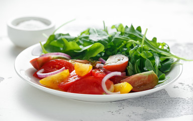 Colorful Tomato Salad with wild rocket in a white plate. healthy food