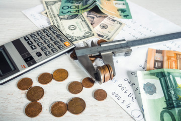 Counting money.  Vernier caliper, money,  coins,  calculator and  paper sheet on desk.