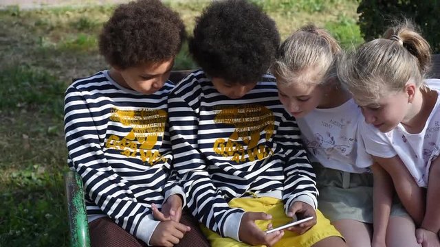 The gudjets generation. Children cant take their eyes off from the phone. kids playing the phone. Twins identical  girls. Mixed boys twins not identical. 