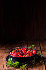 Bowl with different fruits such as strawberry, red currant, and cherry.