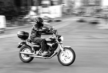 Black and white photo, motorcyclist rides around town, motorcycle
