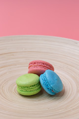 colorful macaroons in wood plate on pink background.
