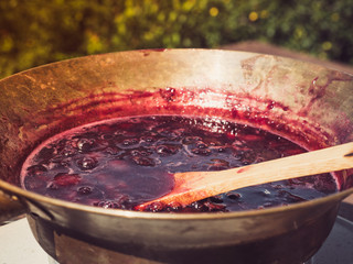 Old, copper pan, wooden spoon and plum jam. We cook outdoors. Preparations for the winter