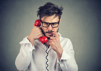 Anxious man speaking on phone receiving bad news