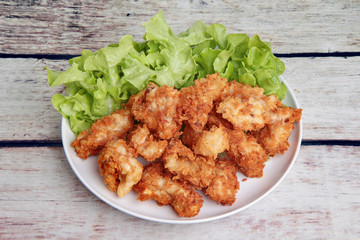 Crispy deep fried chicken served with green oak .