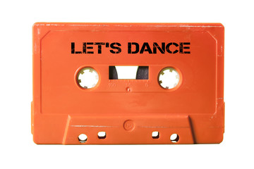 Obraz premium A vintage cassette tape from the 1980s era (obsolete music technology) with the text Let's Dance printed over it (my addition, not in the original image). Color: coral red. White background. 