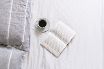 Open book  and cup of coffee in bed 