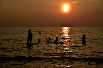 Silhouette einer Familie im Meer bei Sonnenuntergang