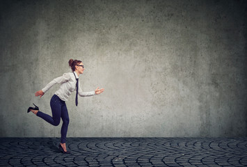 Businesswoman running against gray wall
