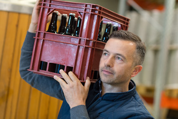 man carrying a box with wine bottles in wine store