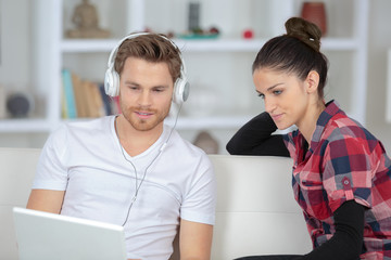Fototapeta premium young smiling couple watching movie on laptop at home