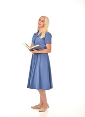 full length portrait of blonde girl wearing blue dress. standing pose holding a book. isolated on...