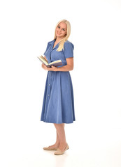 full length portrait of blonde girl wearing blue dress. standing pose holding a book. isolated on white  studio background.