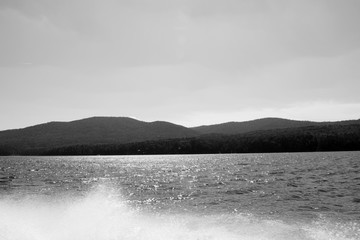 Picturesque view of the rocks surrounded by the sea.  Rocky shore. High mountains against the sky. Sea cruise. Huge space. Wildlife. Beautiful Siberian nature. Black and white photo. Sunset in the mou