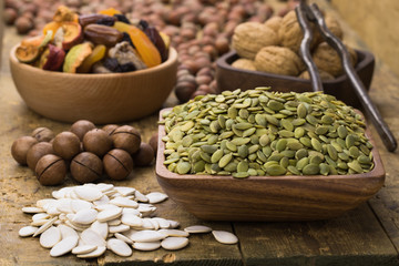 pumpkin seeds peeled in wooden bowl on table, grunge style.