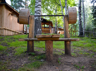 Wooden exercise equipment at the recreation center. Playing sports in the fresh air. Outdoor recreation. Tourist base. Wooden houses in the forest.