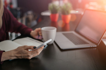 Selective focus on cell phone which young female holding in hand while browsing internet. Close up view of woman reading interesting content via application downloaded to smartphone device.