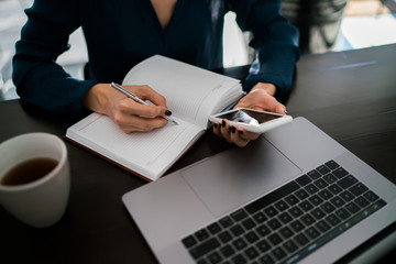 Cropped view of woman typing on smartphone word request for online search in Internet while writing...