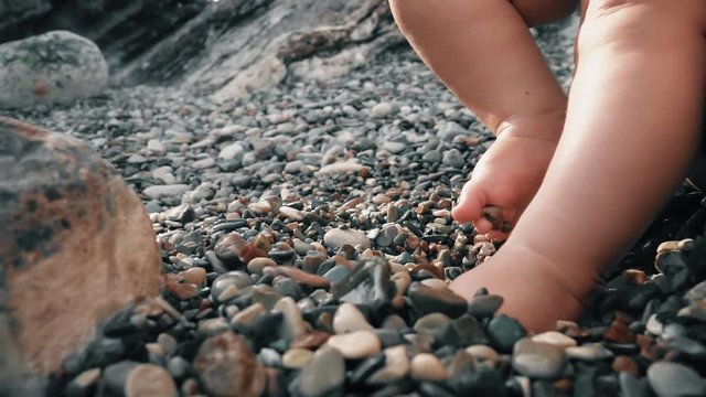 Baby's bare feet on pebble beach, close-up shot