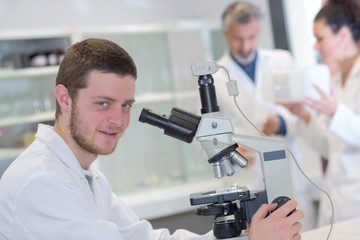 young male scientist with a microscope checking his sample