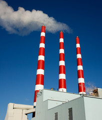 Fototapeta na wymiar Industrial plant smoke stacks and blue sky.