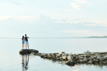 Fototapeta na wymiar Rear view of young couple standing on stones and enjoying beautiful view