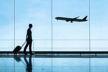 Naklejka premium sylwetka kobiety na lotnisku podróżujących z walizką bagażową, pojęciem podróży i turystyki, bilety lotnicze