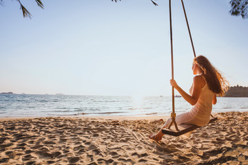 dream and happiness concept, romantic beautiful carefree woman relaxing on the swing at sunset beach, summer holidays, vacation travel and relaxation, inspiring landscape
