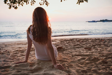 romantic dreams, beautiful girl sitting alone on calm quiet sunset beach, relaxation