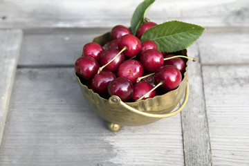 Sweet Cherries in bronze bowl on wooden background
