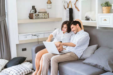 The pregnant woman encourages her husband who is working in the living room at home.