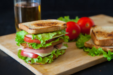 sandwich, tomato, toast, salad and glass with beer on a black ba
