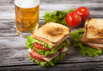 sandwich, tomato, toast, salad and glass with beer on a on a woo