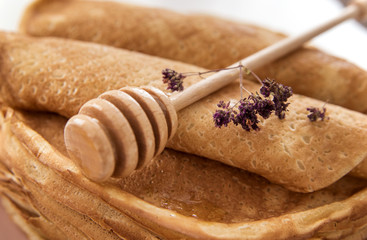 The stick for honey lies on Russian pancakes with purple wildflowers