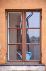 A wooden window with a blue watering can, an orange wall